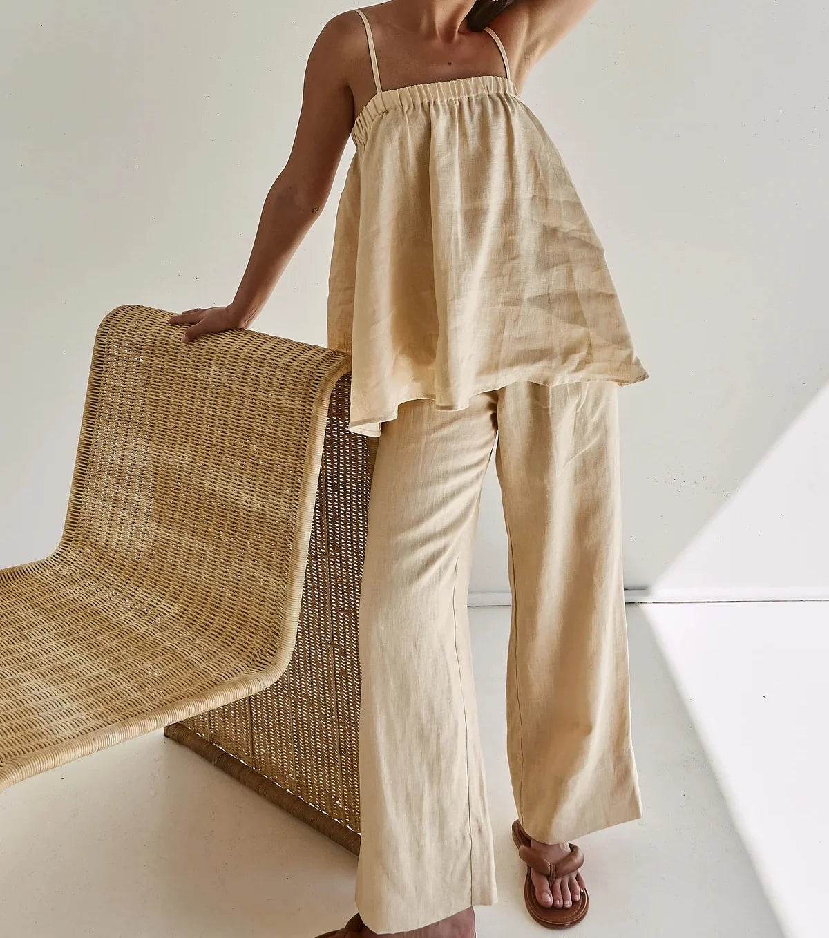Beige cami top and wide leg pants with rattan chair