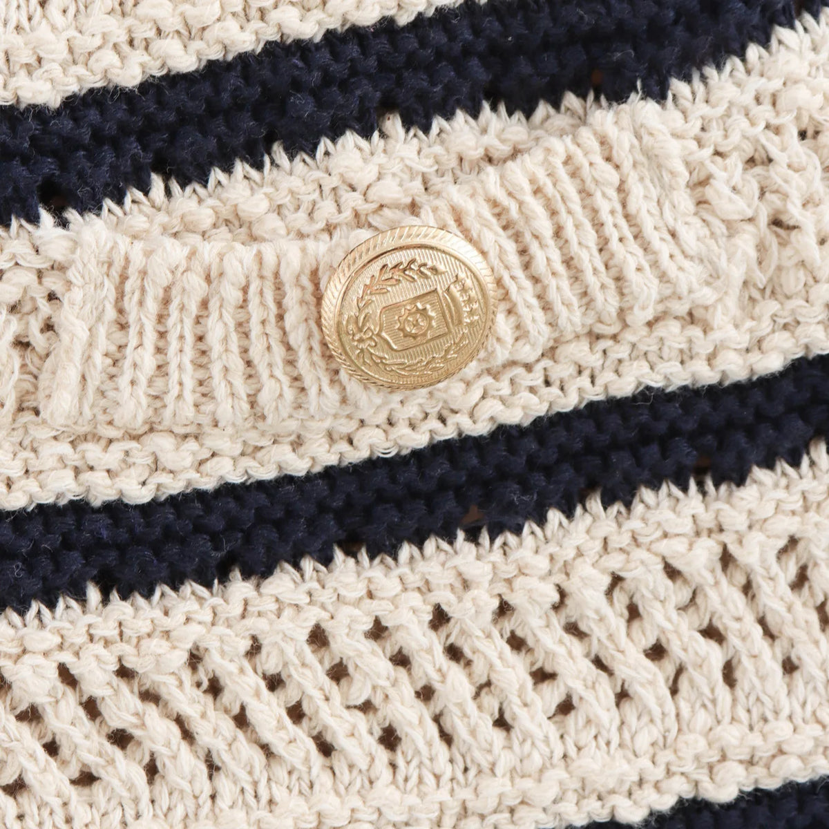 Close-up of gold-tone crest button and knit texture