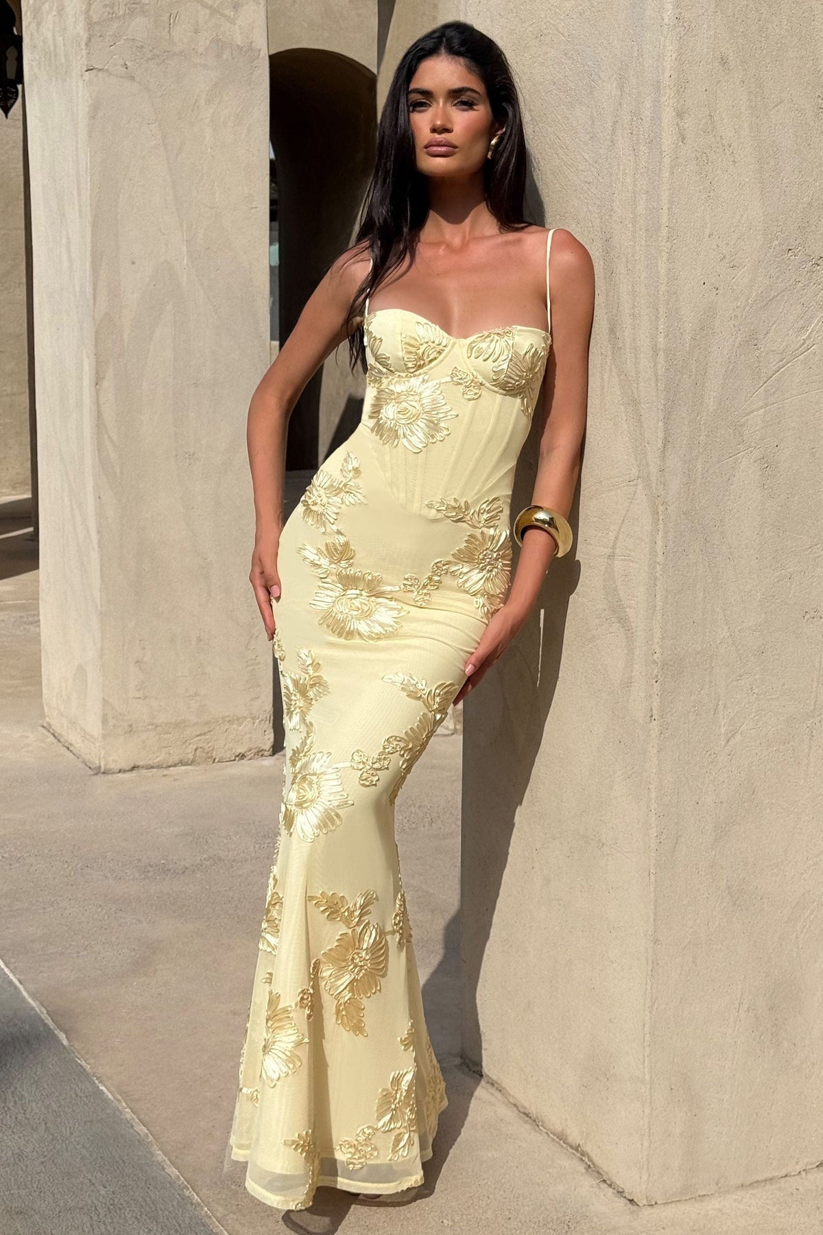 Yellow Floral Appliqué Corset Maxi Dress – lifestyle shot leaning against a stone pillar