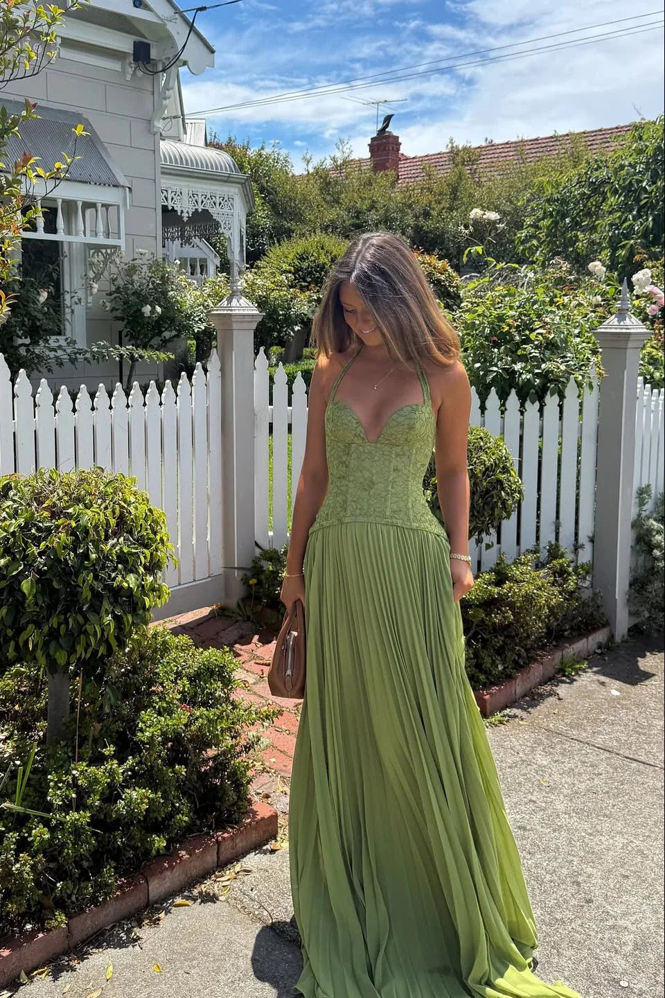 Green Corset Pleated Maxi Dress – lifestyle three-quarter view by a picket fence