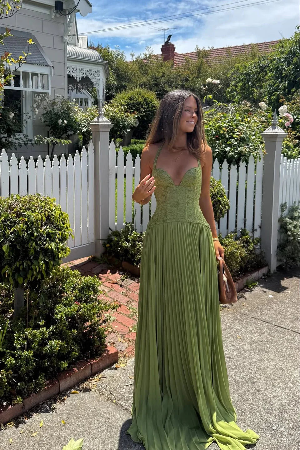 Green Corset Pleated Maxi Dress – lifestyle front view by a white picket fence